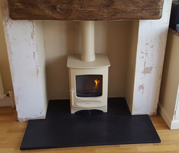 Charnwood C4 Woodburner - in almond with a 48" extremely aged oak beam in medium oak. Installed in Guildford, Surrey